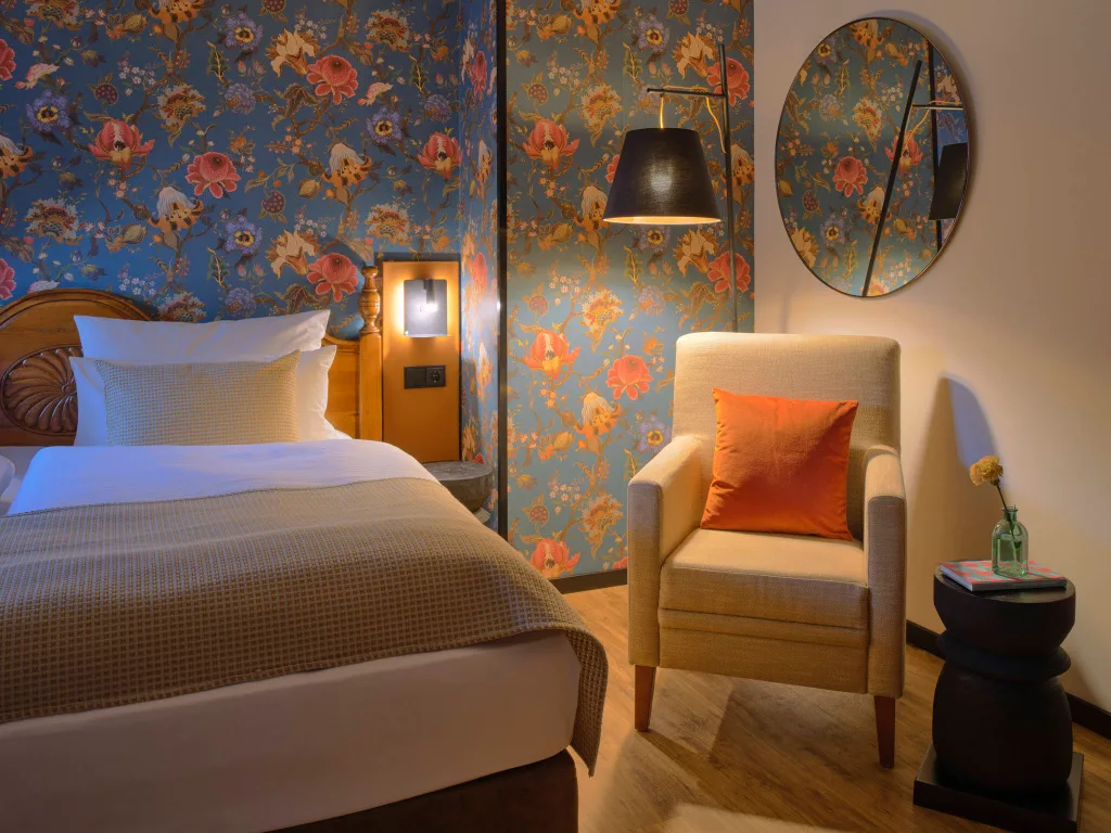 hotel-martinshof-muenchen-premium-3 zimmer-rechte-haelfte-doppelbett-sessel-leselampe-bunte-tapete
