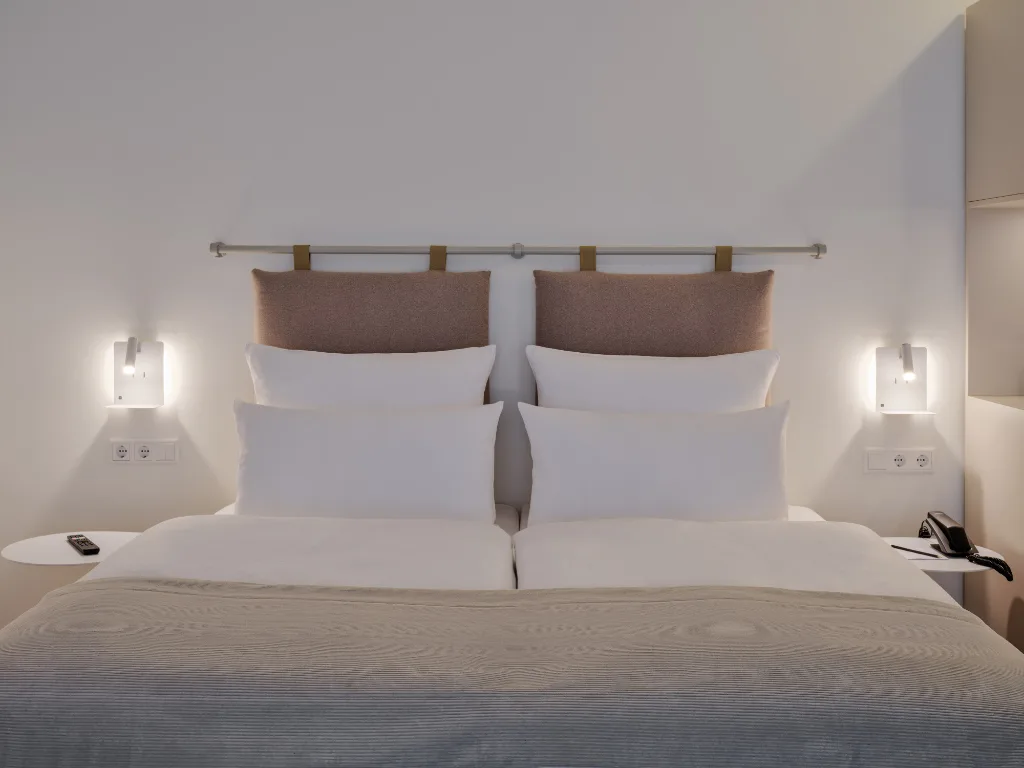 nahaufnahme-kopfteil-doppelbett-helle-bettwäsche-rotbraune-ruekenkissen