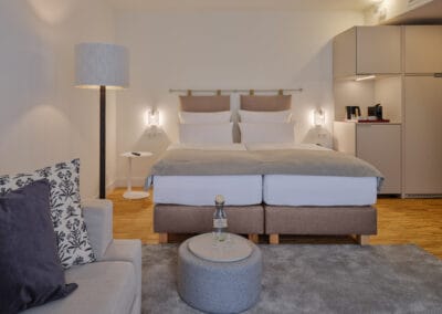 zimmer-mit-blick-auf-das-doppelbett-kleiner-beistelltisch-mit-glaskaraffe