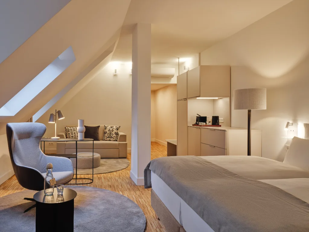 zimmer-mit-optisch-getrennten-wohnbereich-ohrensessel-couch-doppelbett