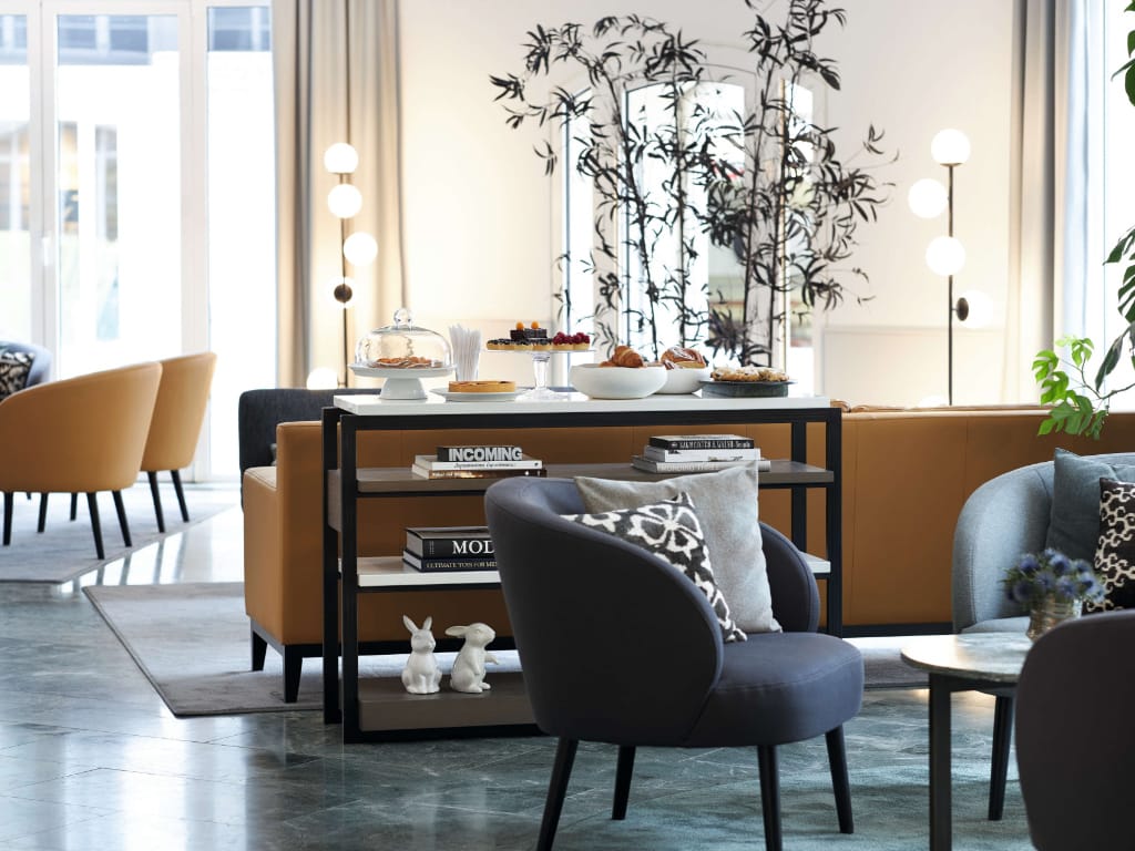 anrichte-fuer-nachmittagskuchen-davor-sessel-mit-bedruckten-kissen