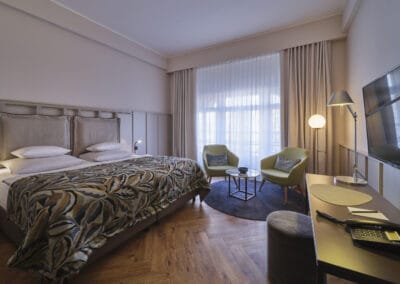 links-doppelbett-mittig-vor-dem-frenster-eine-sitzecke-rechts-ein-schreibtisch-mit-stuhl