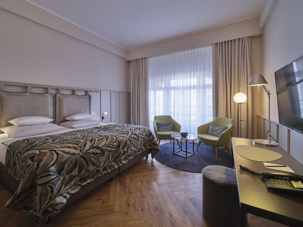 links-doppelbett-mittig-vor-dem-frenster-eine-sitzecke-rechts-ein-schreibtisch-mit-stuhl