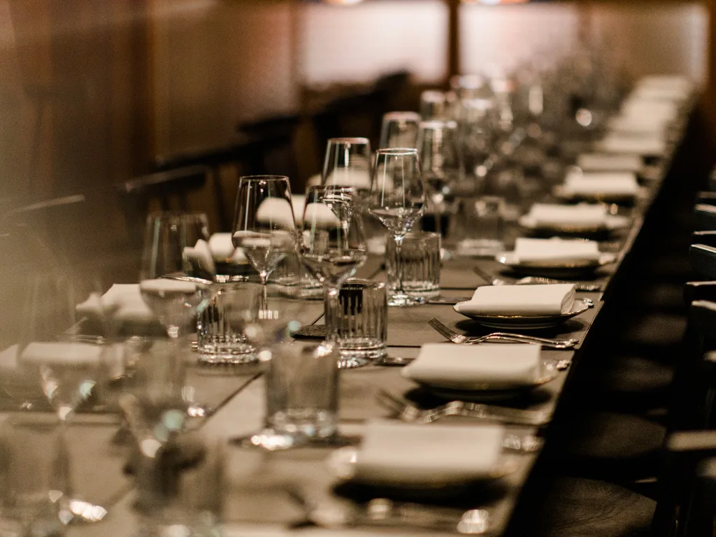 lange-gedeckte-tafel-mit-weissen-flach-aufgelegten-servietten
