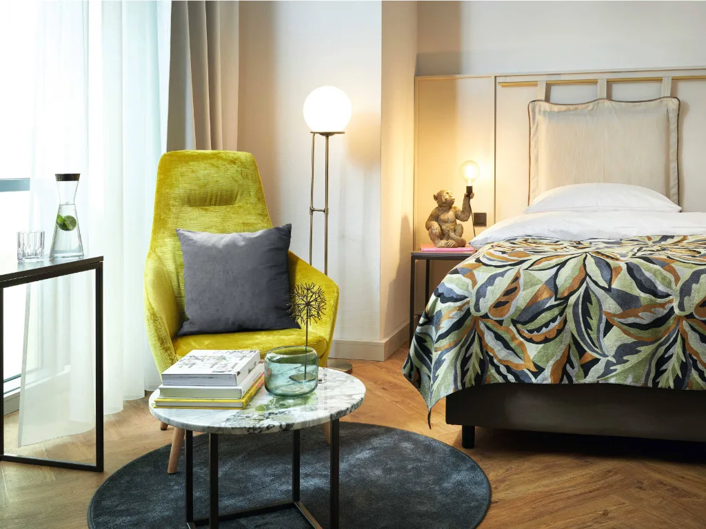 gelber-sessel-mit-beistelltisch-und-einer-affenlampe-neben-dem-bett