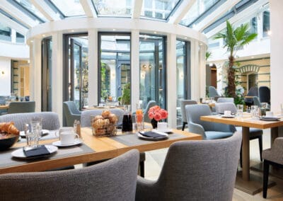 Artrium im Hotel, gedeckter Fruestueckstisch, graue Sessel