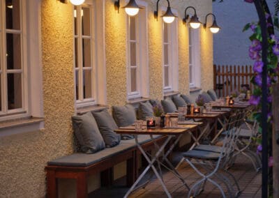 biergarten-bestuhlung-an-gelber-hauswand-mit-laternen