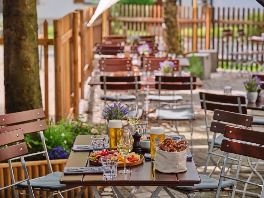 biergarten-mit-tischen-und-stuehlen-bretzelkorb-und-bier-information-öffnungszeiten