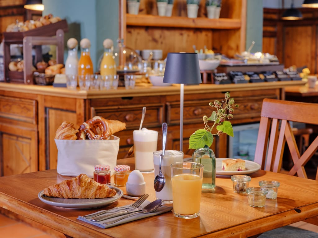 gedeckter-fruehstueckstisch-mit-croissant-orangensaft-und-latte-macchiato