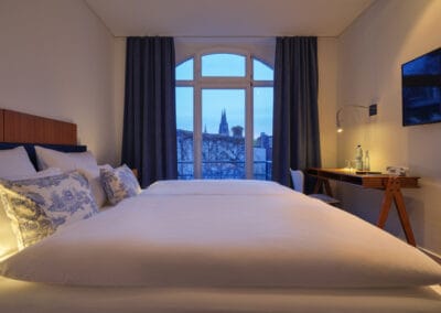 weiss-bezogenes-Doppelbett-grosse-fenster-blick-zum-dom