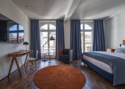 geraumiges-zimmer-mit-schreibtisch-stehlampe-doppelbett-bodentiefen-fenstern