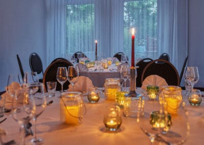 gedeckte-tafel-weisse-tischdecke-leuchtende-kerzen-weinglaeser