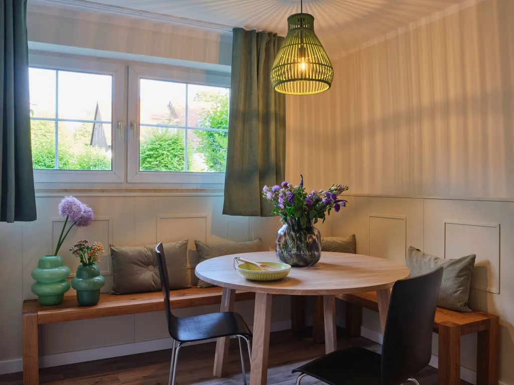 sitzecke-mit-holzbaenke-runter-tisch-schwarze-holzstuehle-fenster-erdgeschoss