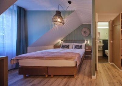 zimmer-mit-blick-aufs-bett-und-ins-bad-schlafbereich-gruen-tapeziert
