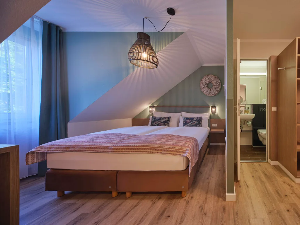 zimmer-mit-blick-aufs-bett-und-ins-bad-schlafbereich-gruen-tapeziert