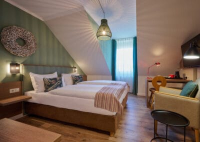 zimmer-mit-doppelbett-sessel-schreibtisch-deckenleuchte-schlaegt-muster-an-die-waende