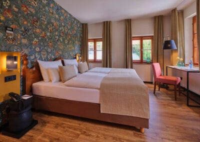 zimmer-mit-blaugemusterter-tapete-okarfarbenen-gardienen-helle-bettwaesche