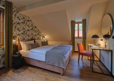 zimmer-weiss-gruen-gemusterter-tapete-schribtisch-darueber-ein-spiegel