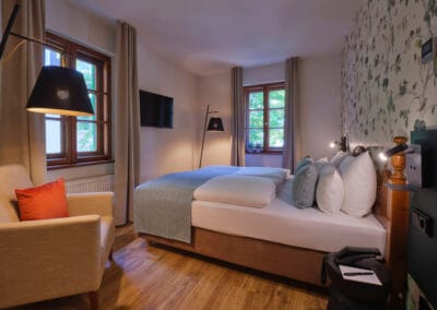 doppelbett-und-sessel-in-hell-tapezierten-zimmer-massivholz