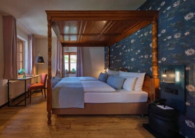 zimmer-mit-himmelbett-und-blauer-tapete-mit-blumenmuster