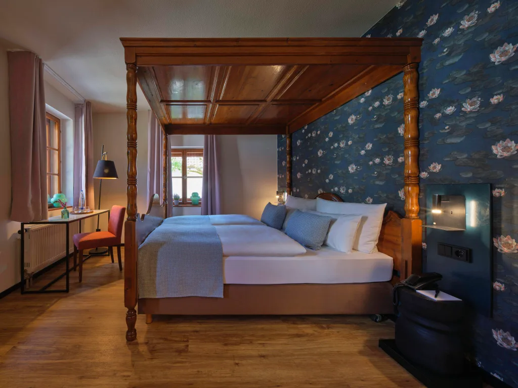 zimmer-mit-himmelbett-und-blauer-tapete-mit-blumenmuster