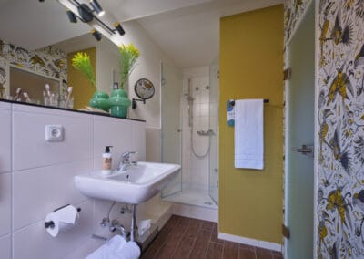 weiss-gefliestes-badezimmer-mit-auffaellig-gelb-gestrichener-wand