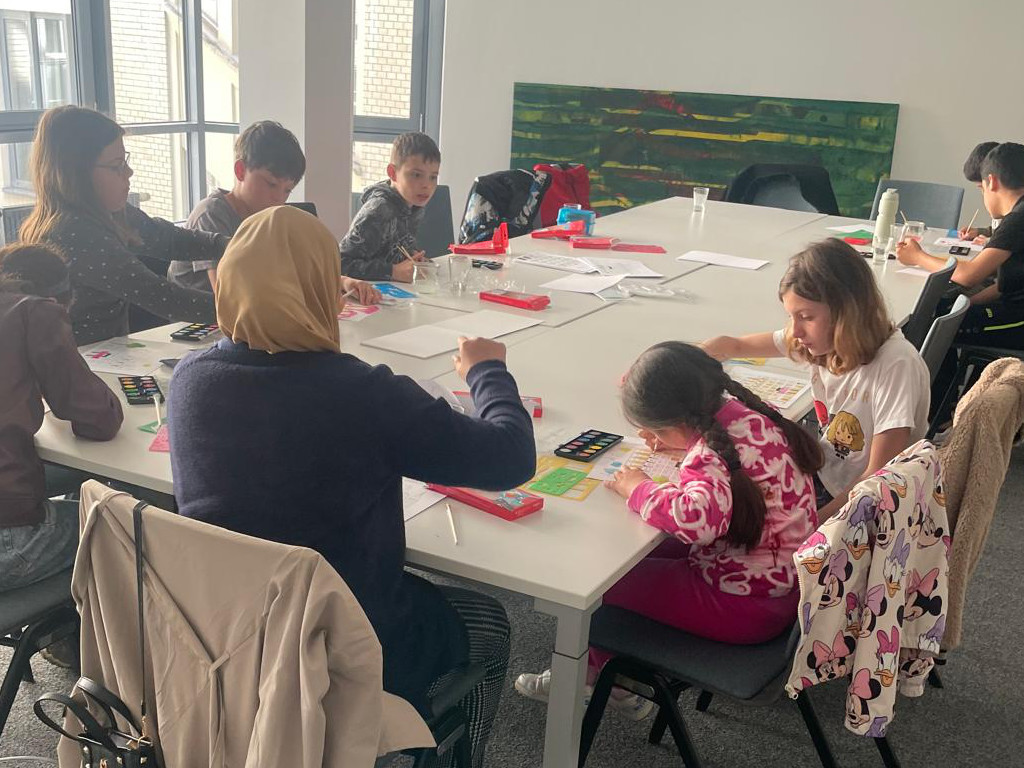 Kinder sitzen am Tisch und malen