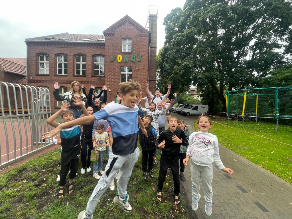 gruppenfoto kind springt vor der kamera in die lust
