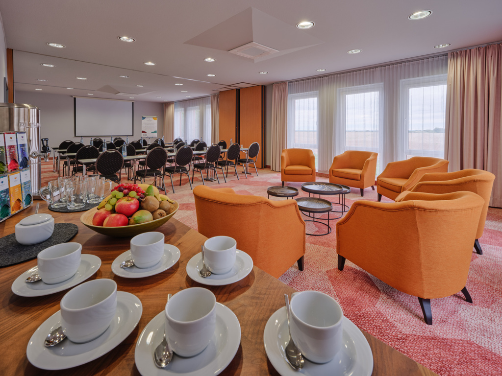 hotel-magdeburg-meeting-6 tagungsraum-kaffeetassen-auf-anrichte-orangene-sessel-parlamentarische-bestuhlung