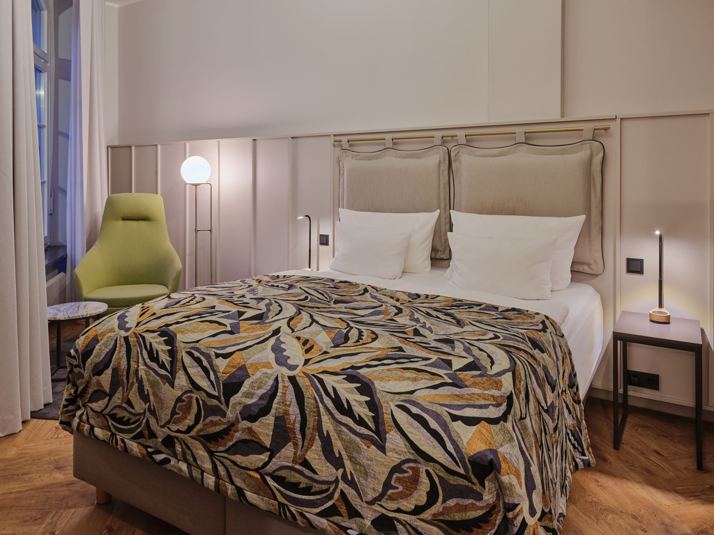 doppelbett-bunte-tagesdecke-gruen-gelber-sessel