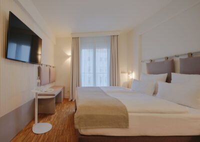 weiss-bezogenes-doppelbett-sitzbank-tv