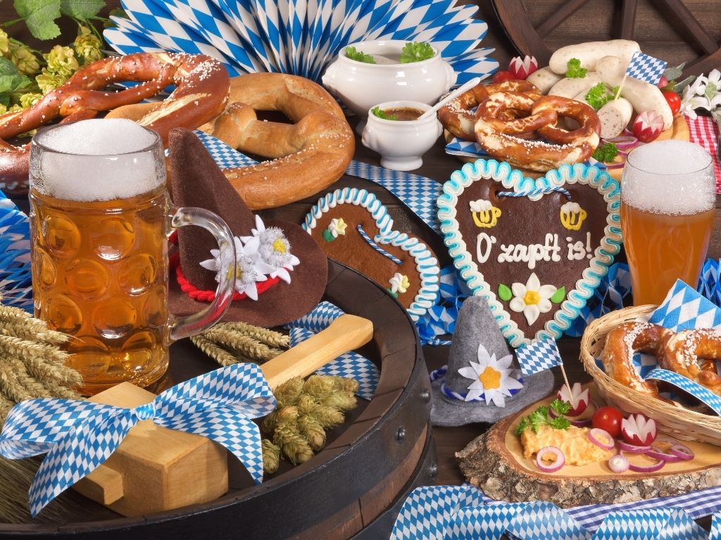 Gedeckter Oktoberfest-Tisch mit Bier, Brezeln und Lebkuchenherzen