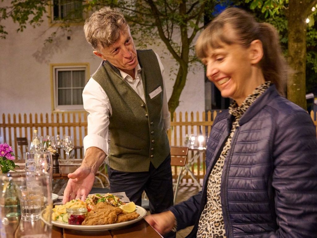 Kellner serviert Essen im Hiergarten Gasthaus Martinshof.